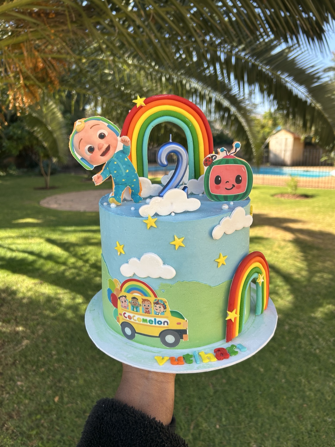 Blue Cocomelon second birthday cake with rainbows and clouds