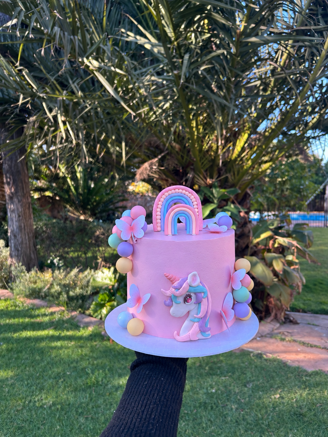Pink rainbow unicorn cake with pastel butterflies and decorations