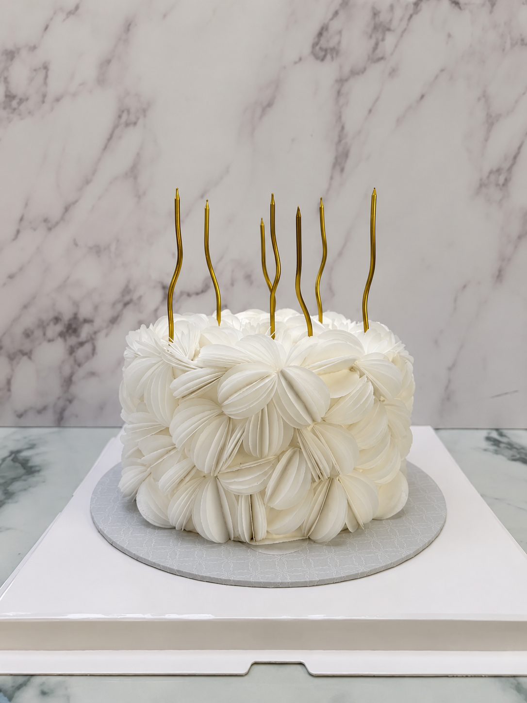 White wafer-paper signature cake with gold candles